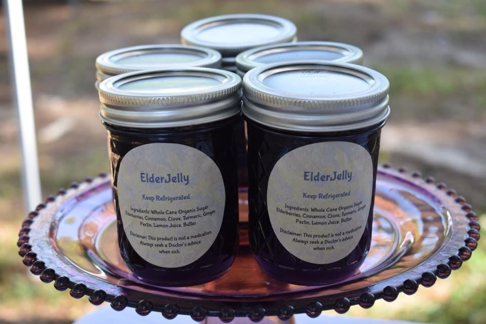 Five jars of small-batch Blessed by Elderberries ElderJelly displayed on a glass serving platter