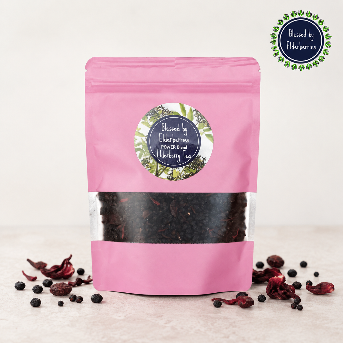 Pink Power Blend Elderberry Herbal Tea bag with dried elderberries, cranberries, and hibiscus on a light countertop