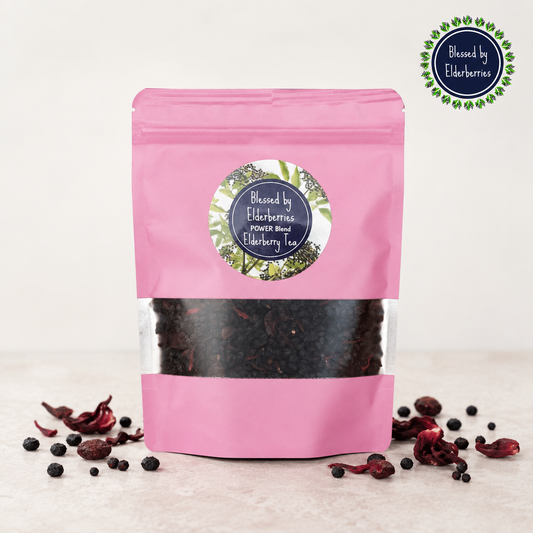 Pink Power Blend Elderberry Herbal Tea bag with dried elderberries, cranberries, and hibiscus on a light countertop