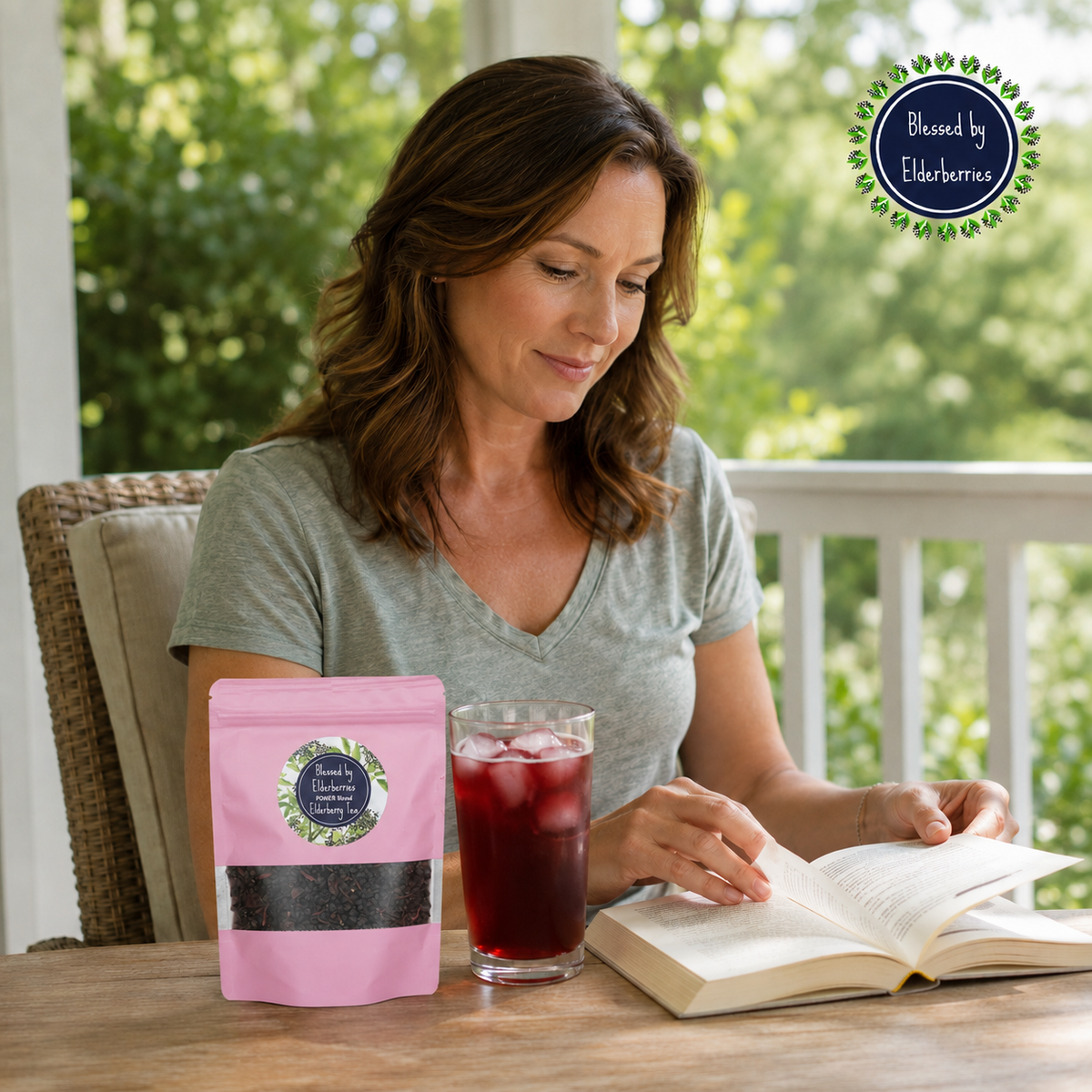 Woman reading on a sunny porch beside a pink Power Blend tea bag and a glass of iced elderberry herbal tea