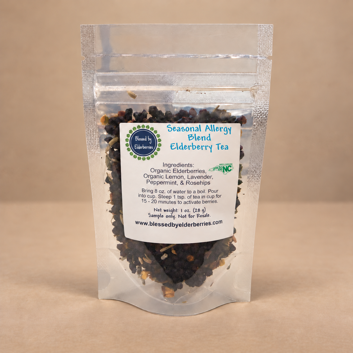 1 oz clear pouch of Seasonal Allergy Blend Elderberry Tea with visible loose-leaf herbs on a warm tan background.